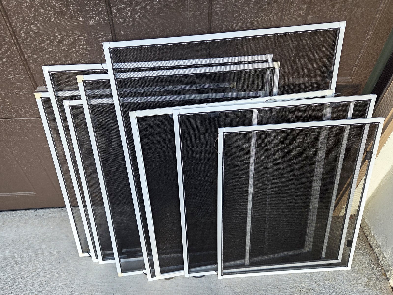 Completed white-framed window screens grouped together after the Carlsbad project